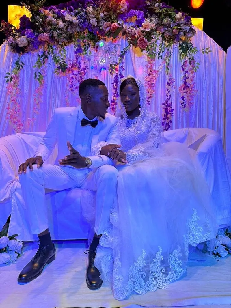 A bride and groom beneath the floral arch at their reception